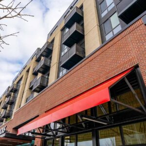 Glass railing on balconies of multifamily apartment complex along with metal awnings