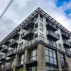 Sun shade around the top level of an apartment complex along with vertical picket railings on balconies