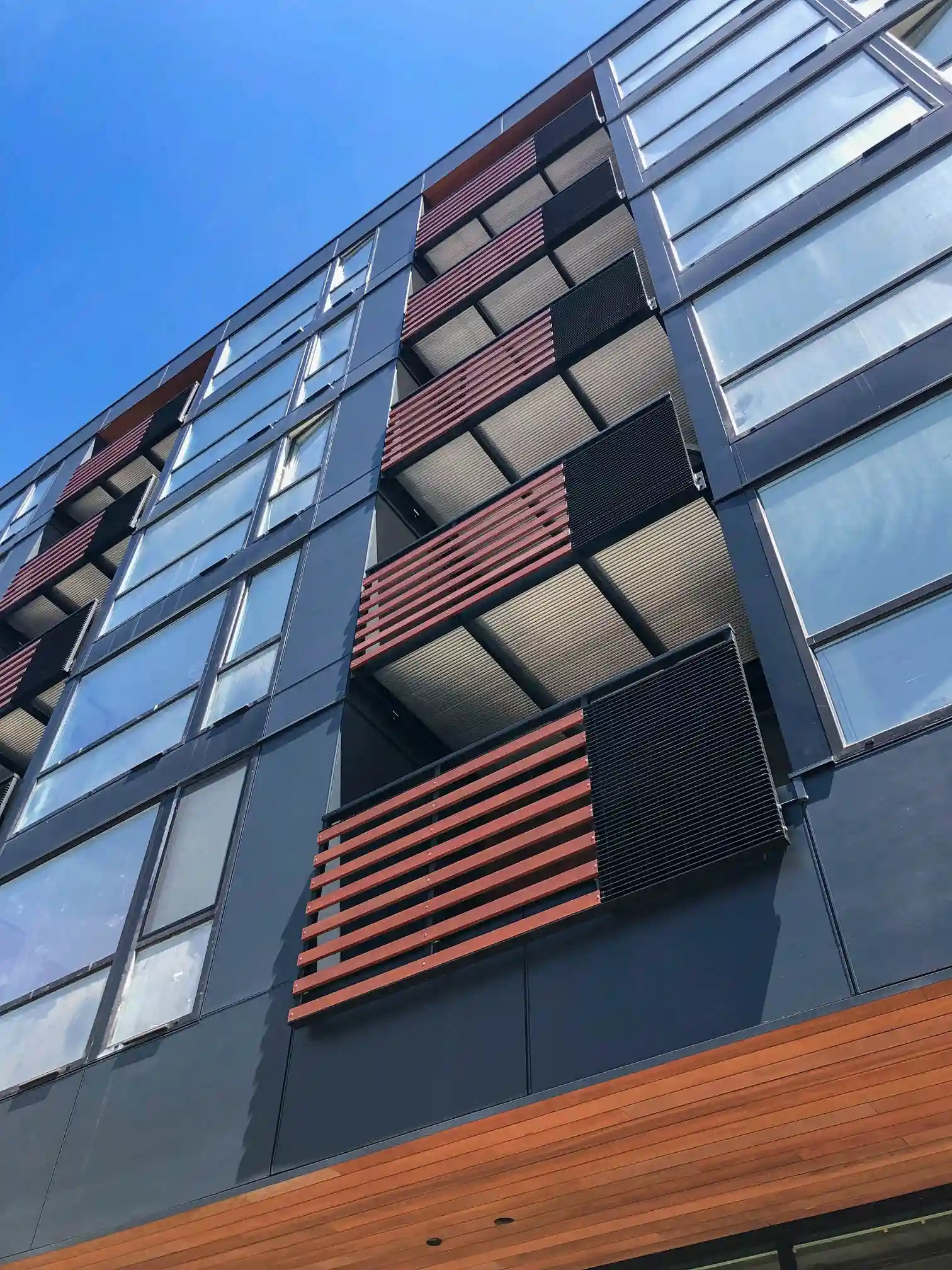 Custom mixed railings including wood and metal on an apartment complex's balconies